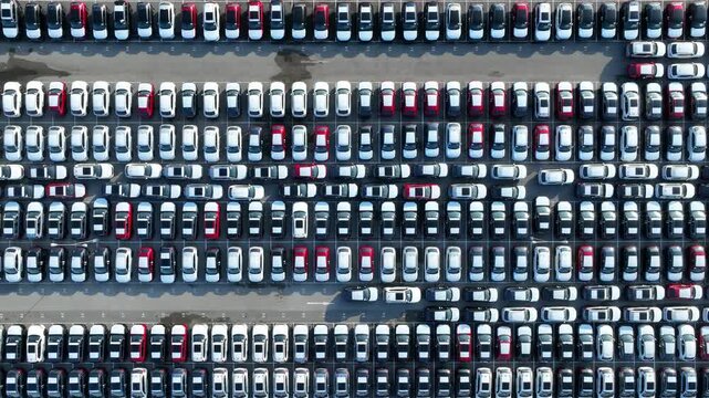 Aerial drone photography of a large-scale car storage lot, illustrating global mobility infrastructure, mass manufacturing operations, inventory data grids, and efficient transportation networks. 4k.
