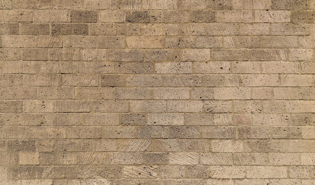 Old porous beige brick wall background with rectangular rough blocks pattern