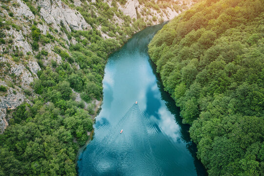 Aerial drone view of two kayaks paddling through a lush forested river canyon Uvac at sunset. Serbian Adventure concept.