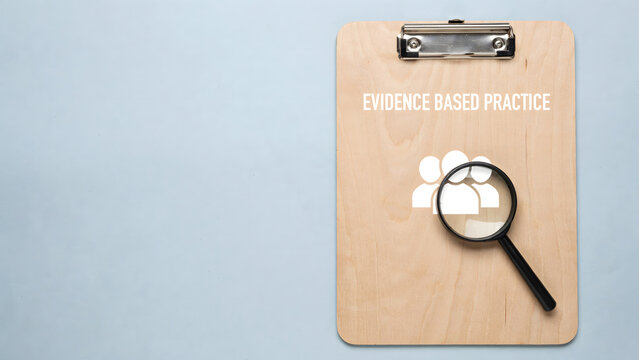 Evidence based practice concept with a wooden clipboard and magnifying glass