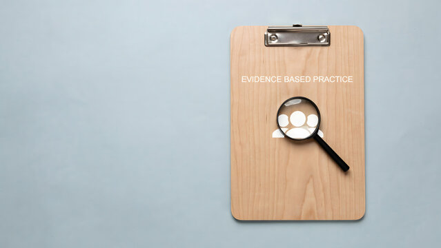 Evidence based practice concept with wooden clipboard and magnifying glass