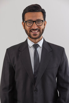 Portrait of a corporate employee in formal business suit smiling against plain backdrop.
