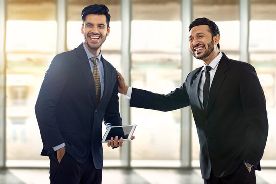 Two corporate employees in formal business suit with one of them selected and the other appreciating with hands on shoulder.