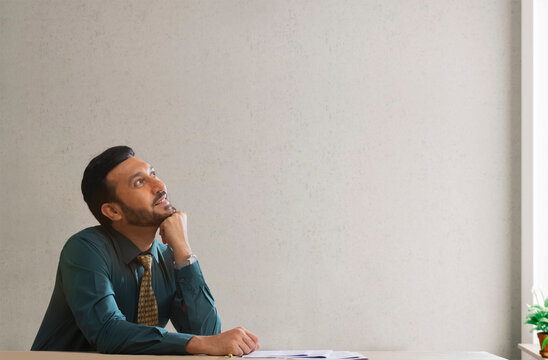  A corporate employee in formal clothing sitting and daydreaming.