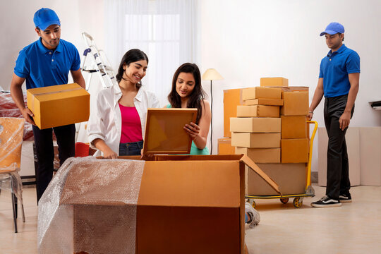 Delivery boys moving carton boxes and helping girls in packing