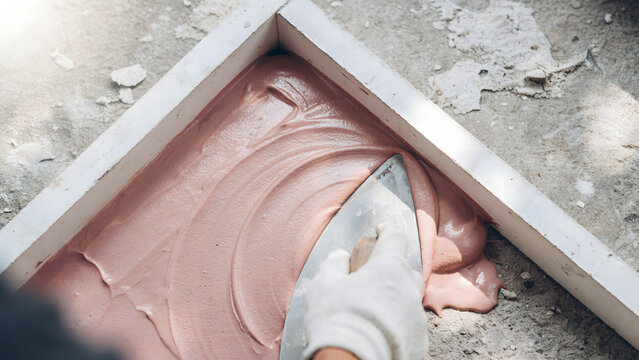 Construction worker applying plaster onto a surface inside a wooden frame