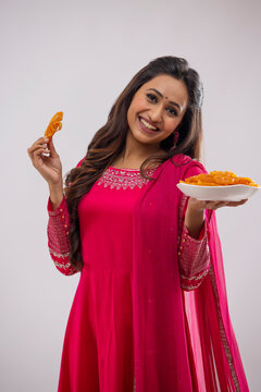 Indian woman standing with a tray full of jalebi on festival