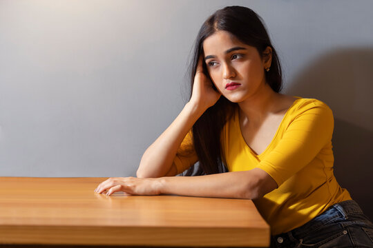 Unhappy young girl looking away with hand on cheek
