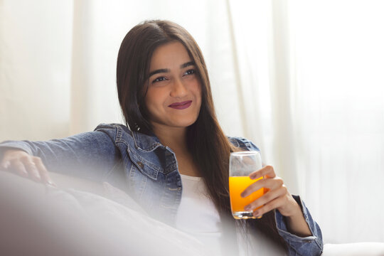 Young girl with a glass of juice looking away with smile