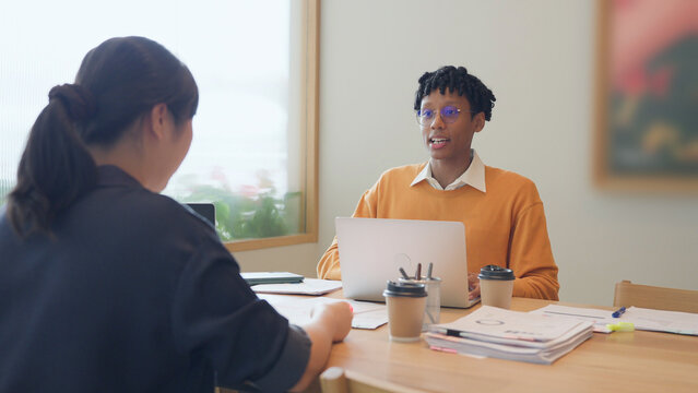 Young African American businessman talking and discussing project with Asian colleague in modern office