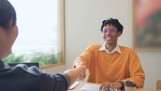 Cheerful African American businessman shaking hands with colleague after a successful meeting in modern office