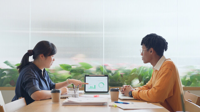 Diverse young colleagues working together on laptop computer in modern office, business collaboration concept