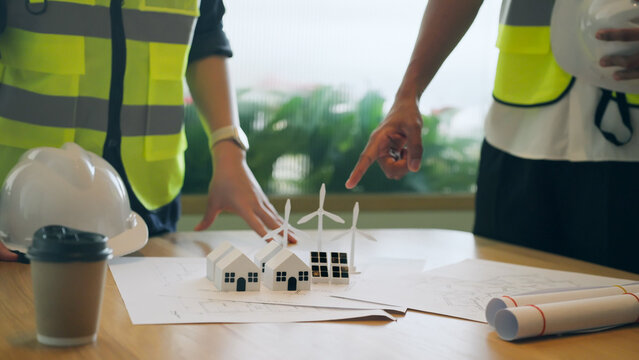 Engineers planning renewable energy project with eco house models and wind turbines
