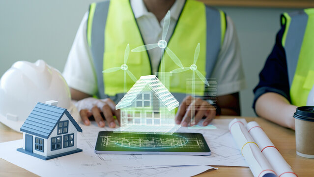 Engineer presenting smart home 3D hologram with wind turbines for renewable energy project.	
