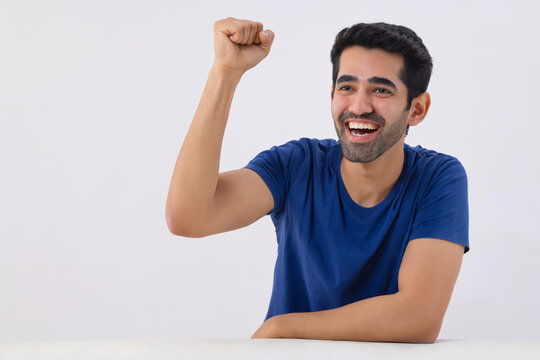 Portrait of a young man celebrating victory by raising his fist