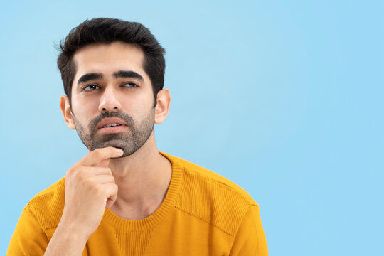 Portrait of a young man looking away and thinking with his hand on chin 