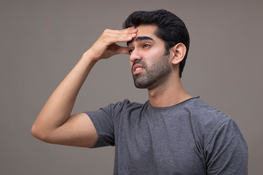 Portrait of a young man suffering from headache with hand on forehead 
