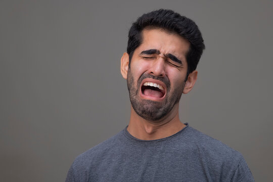 Portrait of a sad young man crying with eyes closed