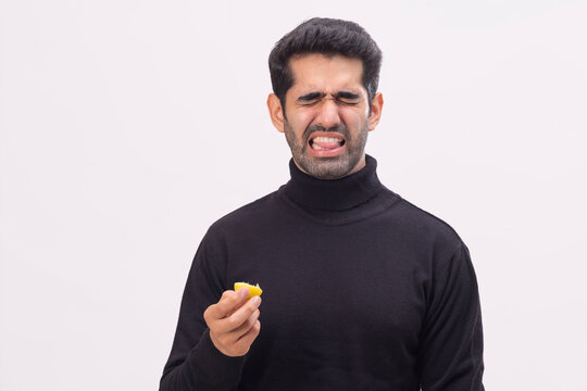 Expression of a young man after sucking sour lemon