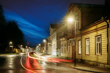Illuminated historic wooden buildings and car light trails on Kuressaare street at winter night © Great Brut Here