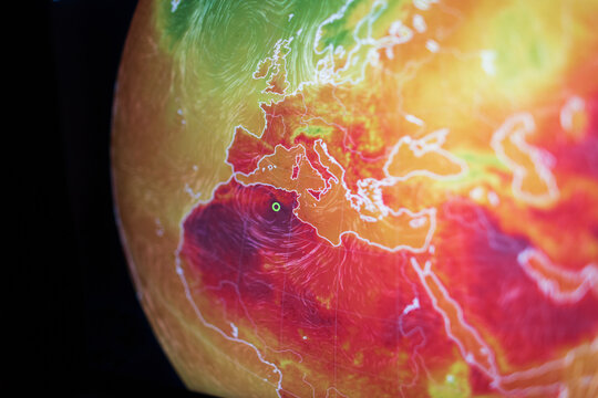 Shallow depth of field shot of a digital globe displaying extreme heatwave anomalies across Europe and Africa. A stark visual concept of global warming and the urgent climate change crisis