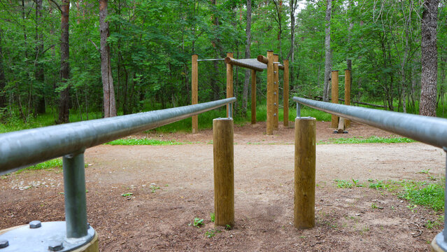 Parallel bars and various wooden fitness stations creating an outdoor workout area, promoting physical activity and healthy lifestyle in a natural environment