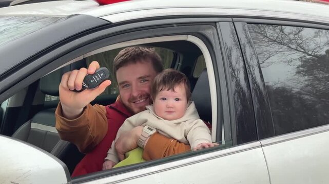 Father smiles while holding key fob beside baby seated near open car window with bright daylight, tree reflections, cozy family travel moment and safe child ride inside vehicle