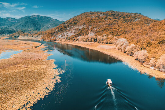 Aerial view of a boat traveling on Rijeka Crnojevica river, Skadar lake national park, Montenegro, surrounded by mountains and wetlands