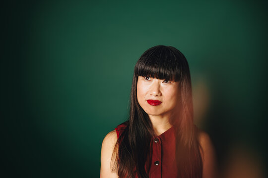 Woman portrait in red top with thoughtful expression in studio