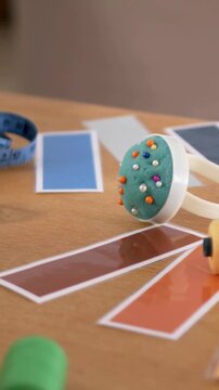 Vertical video: Panning camera drawing pincushion into focus at table for swatches with blue tape