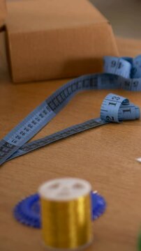 Vertical video: Panning camera moving across craft table, showing gold bobbin, measuring tape, box