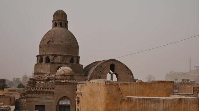 Cairo City of the Dead, Egypt, one of world's largest cemeteries, historic Islamic domes and mausoleums rising above residential tomb buildings and palm trees.