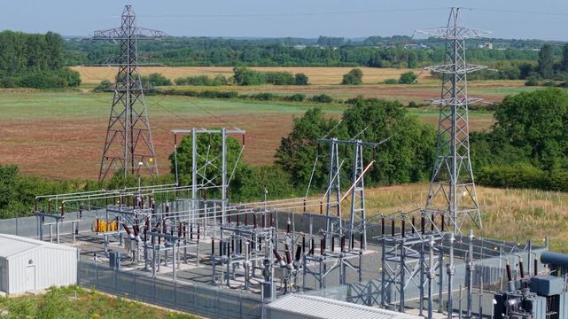 Detailed aerial view of small electrical substation and high voltage power line pylon in rural field