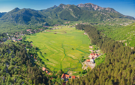 Njegusi village nestled in a green mountain valley, surrounded by lush forests and towering peaks, offering a scenic panorama of Lovcen National Park