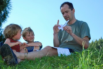 Rodzinna zabawa z papierowym samolotem na słonecznej łące © siwyk