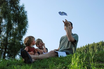 Rodzinna zabawa z papierowym samolotem na słonecznej łące © siwyk