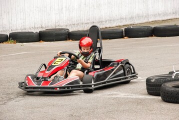 Dziecko prowadzące gokart na torze kartingowym w czerwonym kasku © siwyk