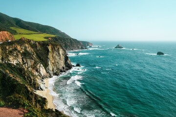 Fototapeta premium Dramatic coastal cliff with crashing ocean waves. Scenic seaside landscape featuring rugged shoreline and turquoise waters.