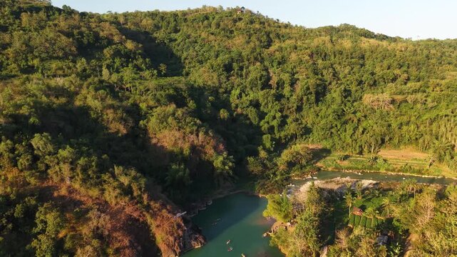 A cinematic aerial view of the Oya Valley in Kedungjati, a tranquil and clean river and canoeing destination. Located in Sriharjo, Bantul, Indonesia.