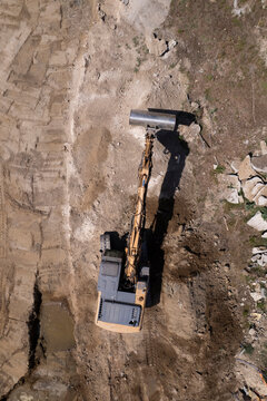 Excavator and dump truck performing earthmoving work at construction site aerial view