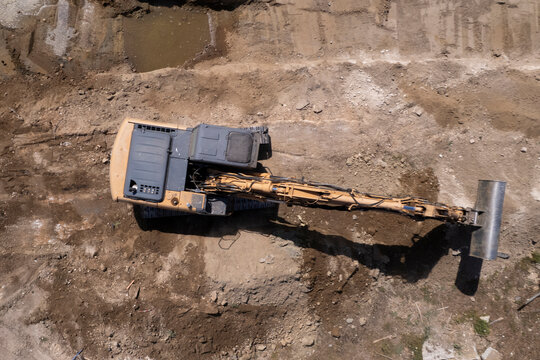 Excavator and dump truck performing earthmoving work at construction site aerial view