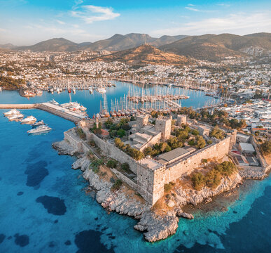Bodrum castle standing over the harbor and marina filled with yachts and boats at golden hour in Turkey