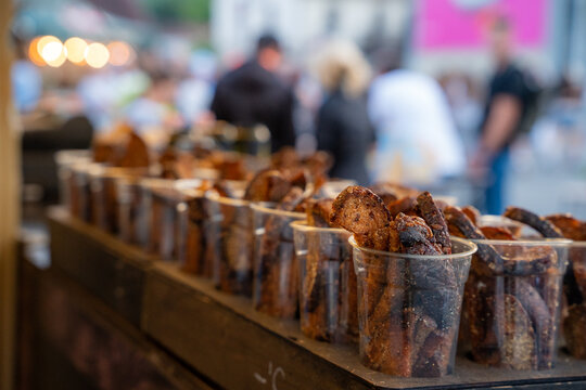 Portions of crispy garlic rye bread snacks served in plastic cups at an outdoor summer event