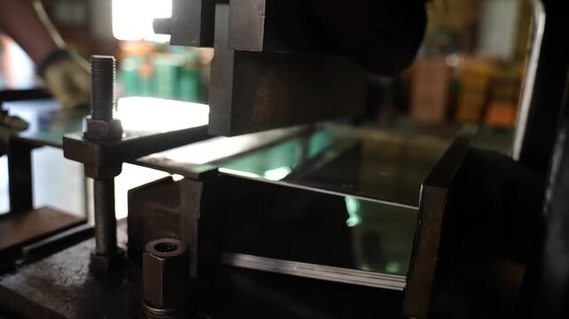 Gloved worker loading polished stainless steel sheets into blanking press at traditional Japanese cutlery factory