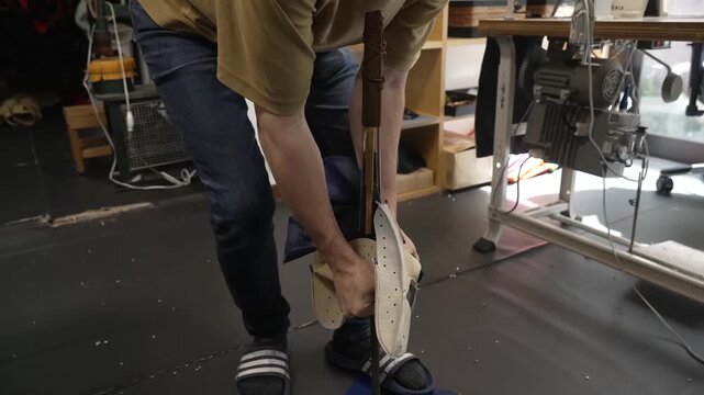 Standing worker turning a leather baseball glove right side out to shape the pocket