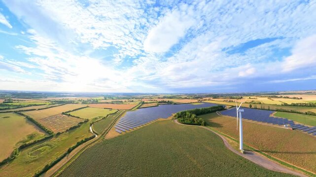 aerial drone footage, Sunset view over a field of renewable energy sources featuring wind turbines and natural scenery. Lincolnshire solar panel arrays wind turbines countryside, England