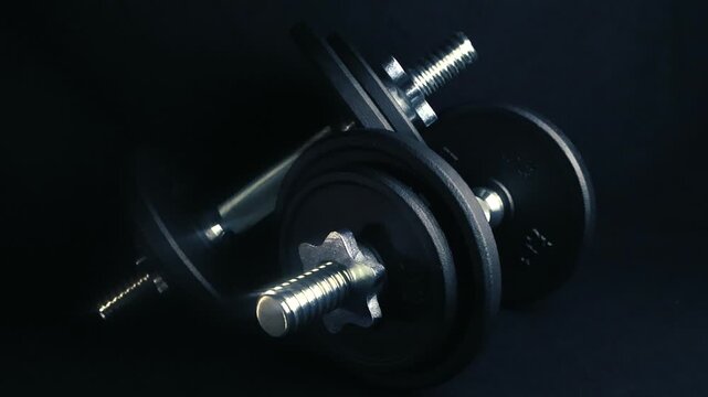 Two adjustable dumbbells with heavy black discs and shiny chrome bars resting on a dark surface, perfect equipment for muscle building, fitness workout, bodybuilding, and home gym routines