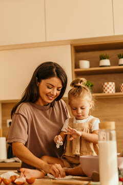Mother and daughter baking cookies in kitchen enjoying family time