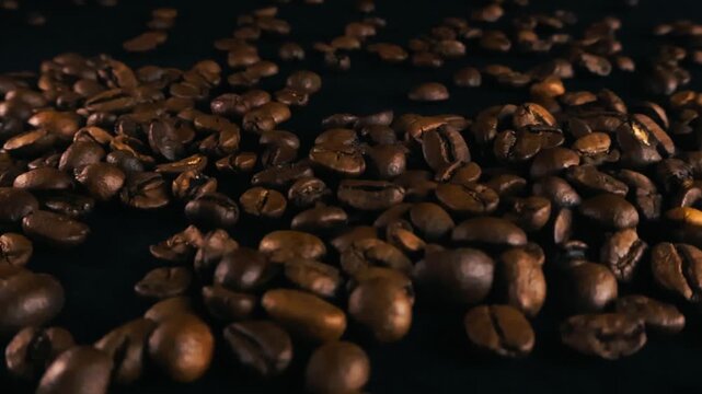 Close up view of aromatic roasted coffee beans gliding across a dark surface, showing rich texture and detail with a shallow depth of field for a cinematic and premium beverage concept