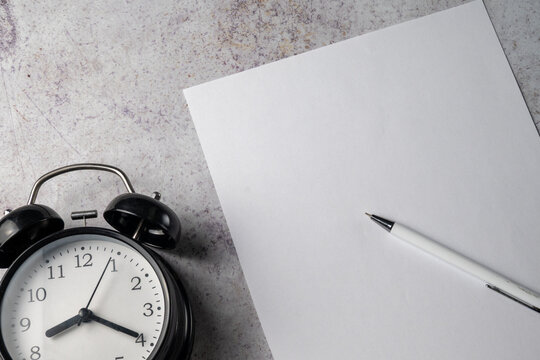 Blank Paper with Pen and Alarm Clock on Desk